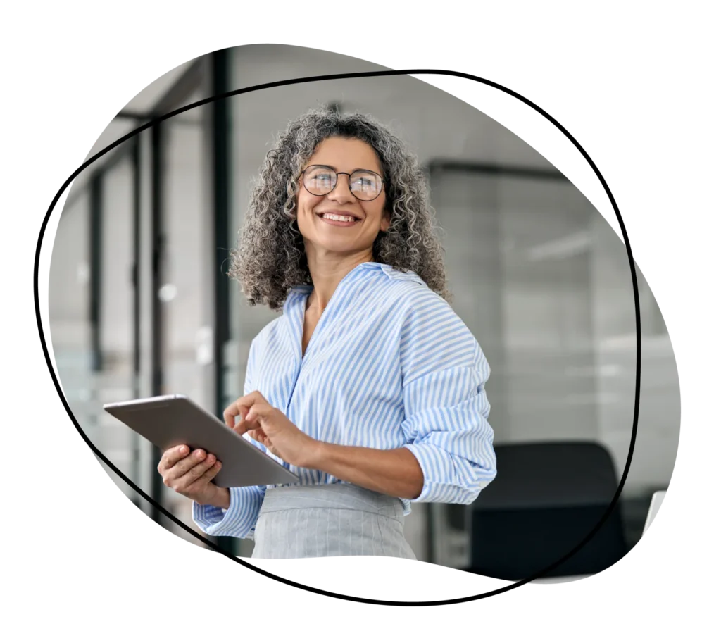 Smiling professional woman holding a tablet in a modern office setting.